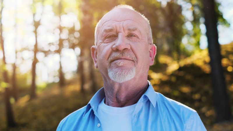 Senior man walking outdoors during sunset
