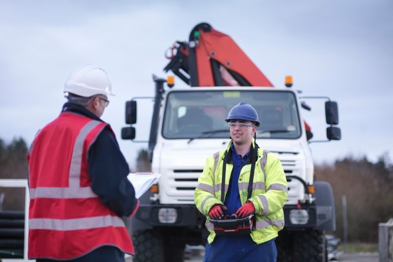 Two blue collar workers standing and talking near a work truck