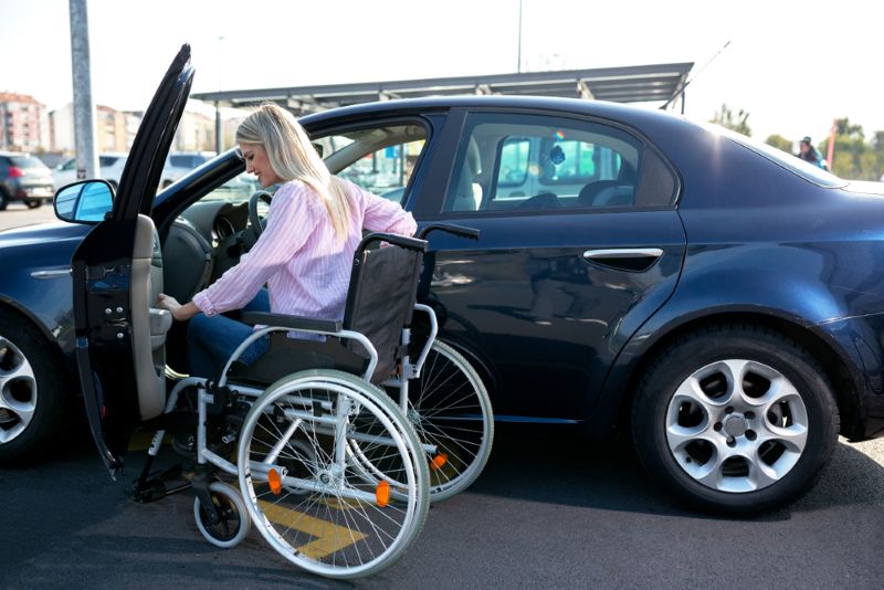 Woman in a wheelchair getting into her car