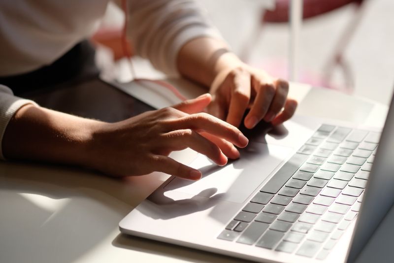 Closeup of a woman's hands typing on a laptop