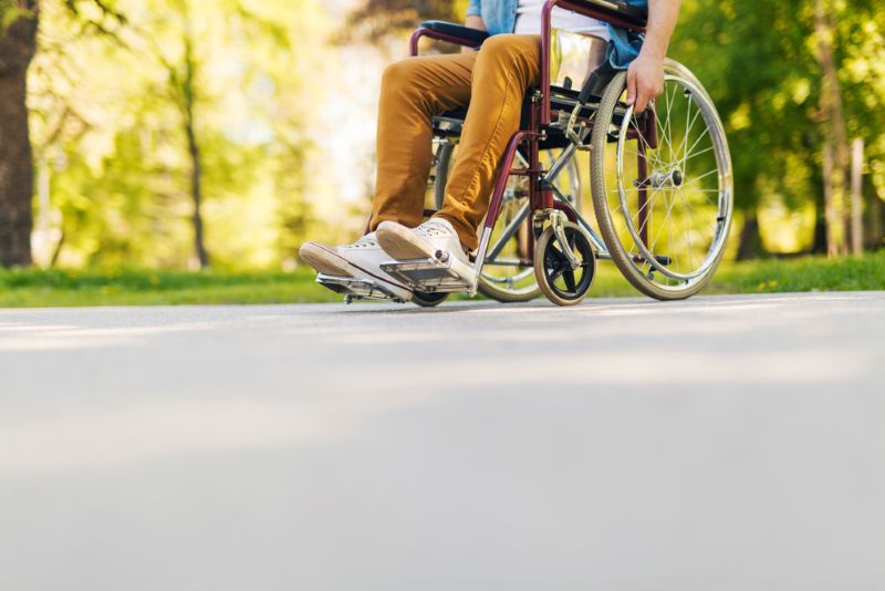 Man strolling through park in a wheelchair