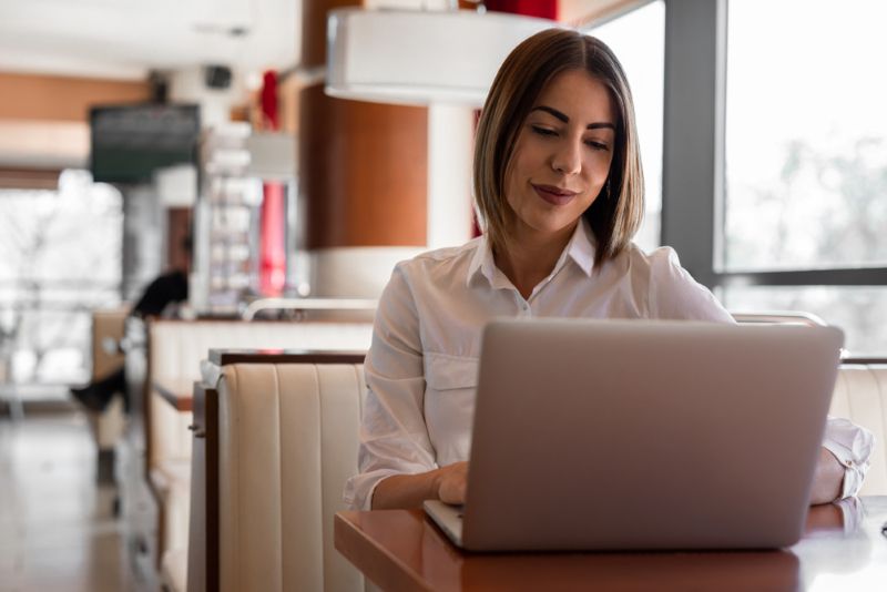 Woman doing research on her laptop from a cafe